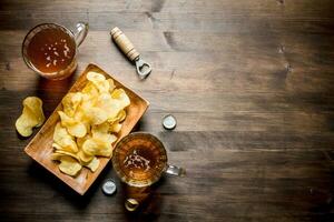 cerveza en vaso tazas y papas fritas en un lámina. foto