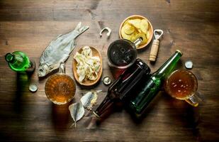 Beer with chips and squid rings in bowl and dried fish. photo