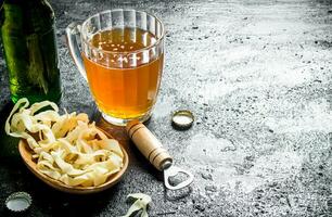 Beer in a glass mug and snacks in the bowl. photo