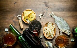 Beer with chips and squid rings in bowl and dried fish. photo