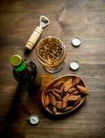 Beer in a glass and a bottle of crumbs in a bowl. photo