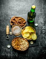 Beer and various kinds of snacks in the bowls. photo