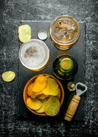 Beer with chips and opener on the cutting Board. photo