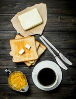 Breakfast. Toasted bread with butter, coffee and orange jam. photo