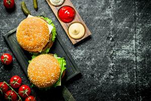 Burgers on the cutting Board and different sauces. photo