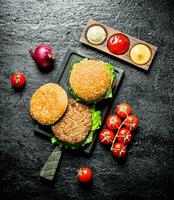 Burgers with tomatoes,sauces and onions. photo