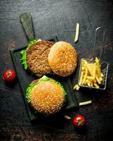 Burgers on a black cutting Board and fries. photo