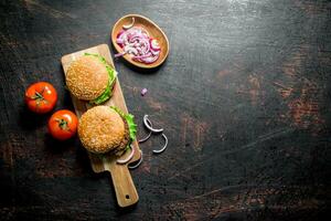 Burgers on the cutting Board and onion slices in the bowl. photo