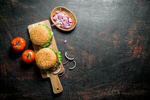 hamburguesas en el corte tablero y cebolla rebanadas en el bol. foto