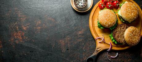 Burgers on a round cutting Board with spices and tomatoes. photo