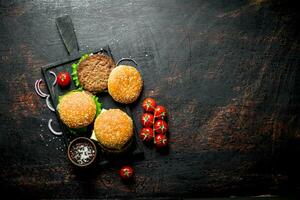 Beef burgers and spices in bowl on cutting Board. photo