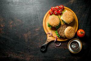 Burgers on a round cutting Board with spices and tomatoes. photo