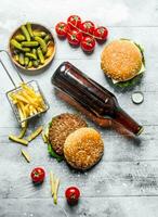 Burgers with beer in a bottle,gherkins and fries. photo