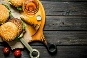 hamburguesas en papel con cerveza y Tomates. foto