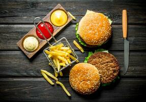 Burgers with fries,sauces and a knife. photo