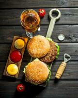 hamburguesas con cerveza en un vaso y diferente salsas foto