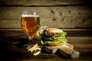 Burger with beer in a glass and fries. photo