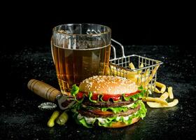hamburguesa con cerveza, papas fritas y pepinillos. foto
