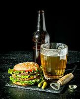 carne de vaca hamburguesa y cerveza en un vaso y botella. foto