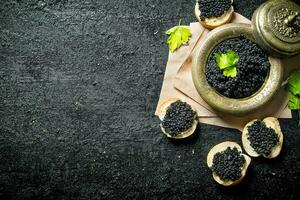 negro caviar en un pan rebanadas y caviar en un cuenco en papel con perejil. foto