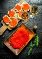 Sandwiches with red caviar and red caviar on a plate with the wine. photo