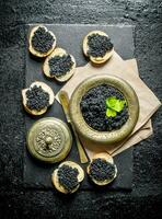 Sandwiches with black caviar and caviar in a bowl on paper with parsley. photo