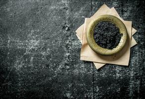 Black caviar in a bowl on paper. photo