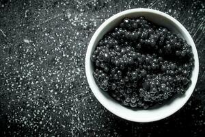 Black caviar in a white bowl. photo