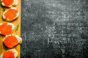 Sandwiches with red caviar on a wooden stand. photo