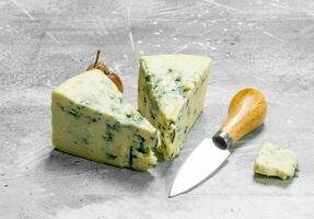 azul queso con un cuchillo y uvas. foto