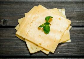 Thin slices of cheese with a branch of mint. photo