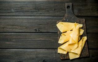 Thin slices of cheese on the cutting Board. photo