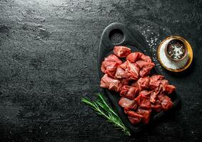 Cut raw beef on a black cutting Board with rosemary. photo