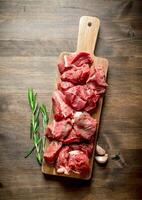 Cut raw beef on a wooden cutting Board with rosemary and garlic. photo