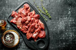 Cut raw beef on a cutting Board with seasonings and oil in a bottle. photo