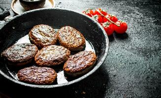 Cutlets in pan with spices and tomatoes. photo