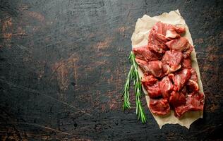 Sliced raw beef on paper with rosemary. photo