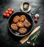 Cutlets in the pan with a wooden spatula and cherry. photo