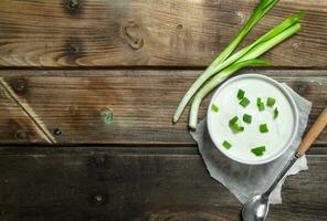 Fresco agrio crema en cuenco con verde cebollas . foto