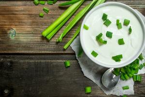 Fresco agrio crema en cuenco con verde cebollas . foto