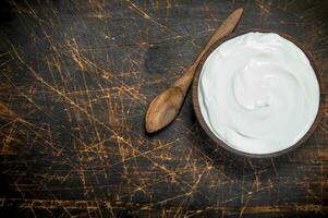 Fresh sour cream in bowl with spoon . photo