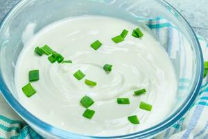 Sour cream in bowl with green onions. photo