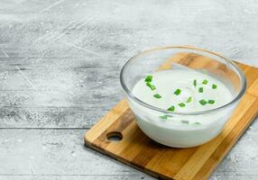 Sour cream in bowl with green onions. photo