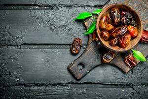 Dates with a bowl with green leaves. photo