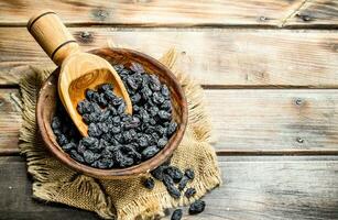 Raisins in a bowl with a wooden scoop. photo