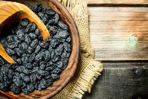 Raisins in a bowl with a wooden scoop. photo