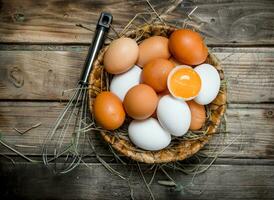 Eggs in a basket with a whisk. photo