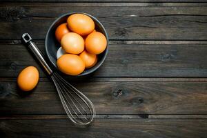 Eggs in a bowl with a whisk. photo