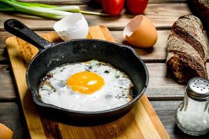 Fried egg in a pan with bread, tomatoes and green onions. photo