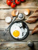 Fried egg in a pan with bread, tomatoes and green onions. photo